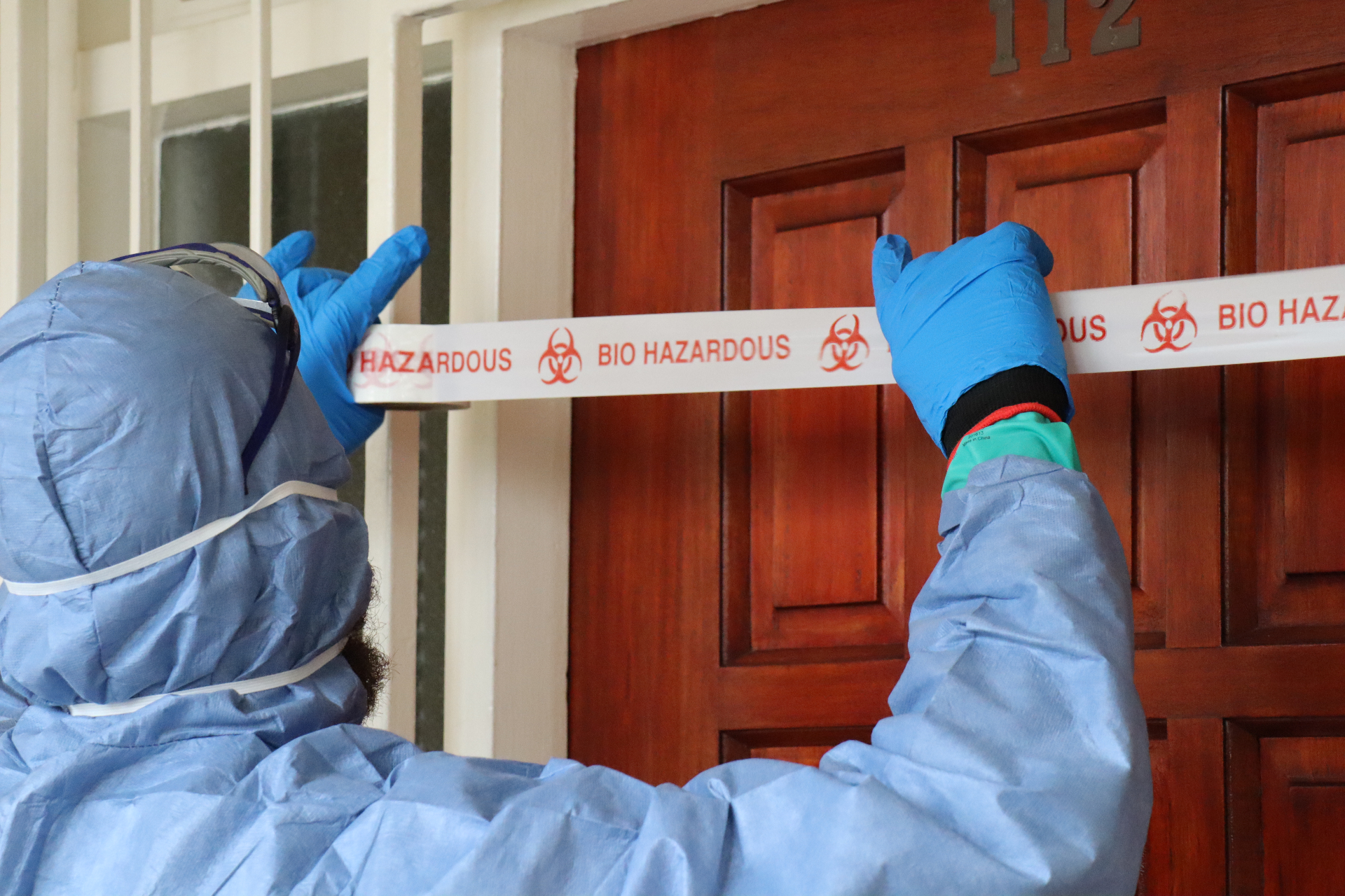 Trauma Cleansing technician sealing a doorway with biohazard tape